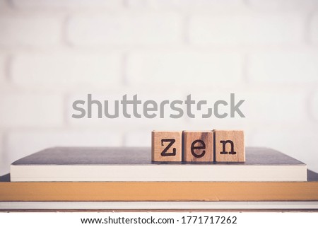 The word ZEN, alphabets on wooden cubes on top of books with bricks background, blank copy space, vintage minimal style. Concepts of Mahayana Buddhism in China, religion, meditation, spiritual.me
