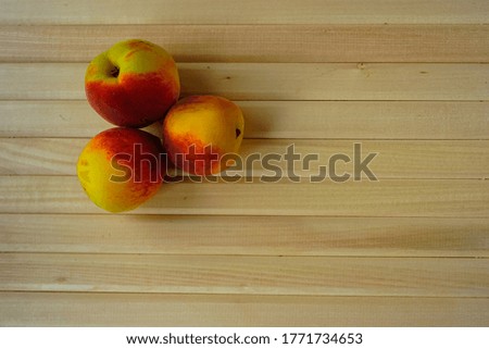 Photo from above. Three juicy ripe peaches are lying on a table of natural wood light boards photographed from a top angle. Fresh fruits - a source of vitamins and sweets for health and diet