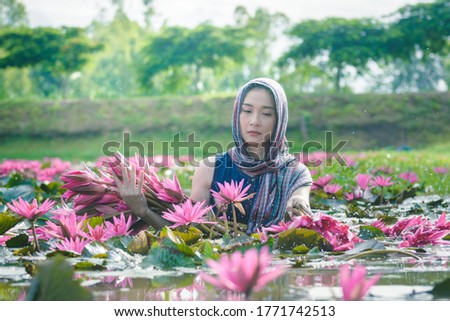 Picture with noise in low light ,Beautiful women wearing Thai dress traditional  holding lotus flower in the lotus lake countryside 