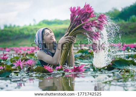 Picture with noise in low light ,Beautiful women wearing Thai dress traditional  holding lotus flower in the lotus lake countryside 