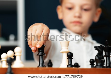 Close up photo of a little boy playing chess