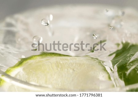 Refreshing lemonade with slices of lime with ice in a transparent sweaty glass cup close-up macro photo