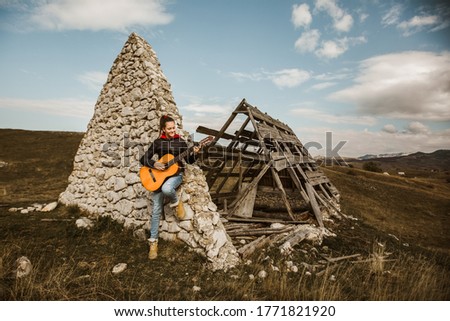 Young girl with a guitar in a mountainous area