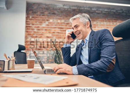 Businessman working in office with computer and talking on phone in the loft office Royalty-Free Stock Photo #1771874975