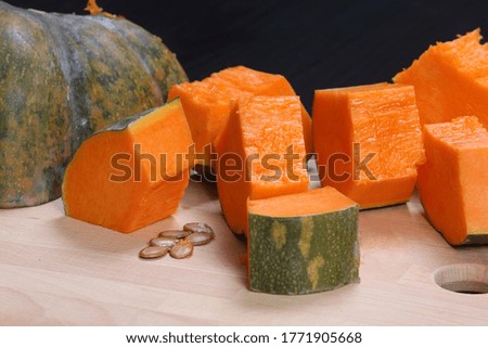 yellow pumpkin cut into pieces on wooden table