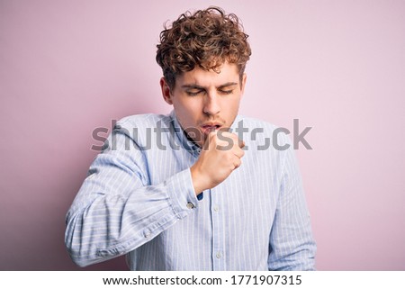 Young blond handsome man with curly hair wearing striped shirt over white background feeling unwell and coughing as symptom for cold or bronchitis. Health care concept.
