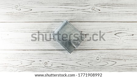 Silver wallet on a wooden board background.