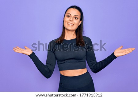 Young beautiful brunette sporty woman wearing casual sportswear over purple background smiling showing both hands open palms, presenting and advertising comparison and balance