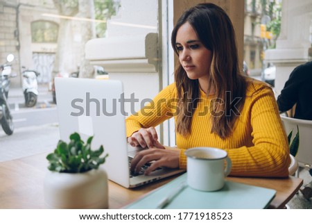 Smiling woman watching video on computer working on freelance in cozy coffee shop, female student rest during free time reading news blogging in social networks using netbook

