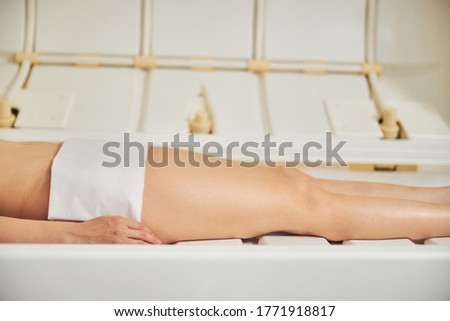 Cropped photo of a Caucasian woman lying in a modern spa capsule during the skin treatment in beauty salon