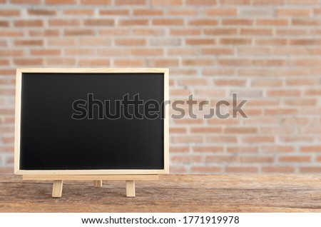 Blank chalkboard on old wood table with brick wall background, Empty chalk board menu standing on vintage wood with copy space for text or message, Product display montage.