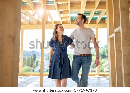 Wife and husband visiting building site of their new house with construction in background Royalty-Free Stock Photo #1771947173