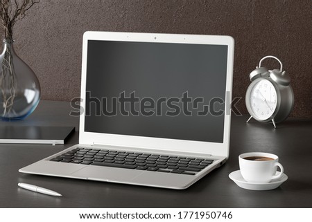Workspace with laptop mock up. Dark wooden desk and brown wall. Side view. Clipping path round laptop screen. 3d illustration