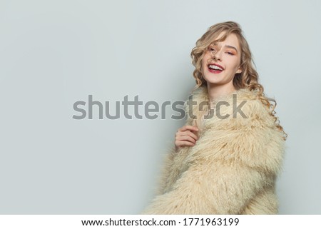 Fashion portrait of happy woman in eco friendly fur coat on white background