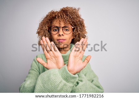 Young beautiful african american woman wearing turtleneck sweater and glasses Rejection expression crossing arms doing negative sign, angry face