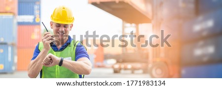 Foreman using radio communication or walkie talkie control loading containers in shipping yard, for logistics company. business logistics concept.