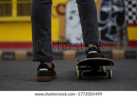 A young man standing while keeping one of his foot on a Skateboard.