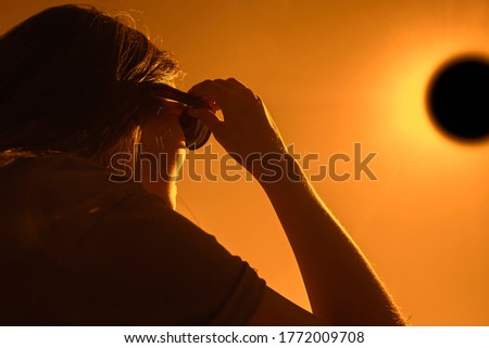 Woman is looking on solar eclipse through three sunglasses. Sun eclipse concept. Royalty-Free Stock Photo #1772009708