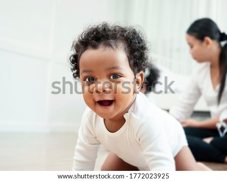 The American Afican boy is crawling and smiling for the camera. Royalty-Free Stock Photo #1772023925