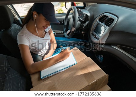 A woman in the car sorting boxes for delivery