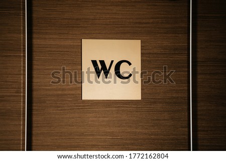 WC sign on a wooden door background. copy space. Beige toilet sign