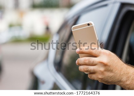 Man uses mobile phone to take a photo from a car window. 