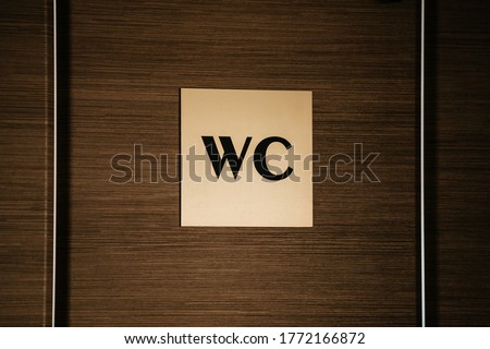 WC sign on a wooden door background. copy space. Beige toilet sign