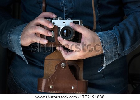 Men in jeans shirt holding an old rangefinder film camera camera