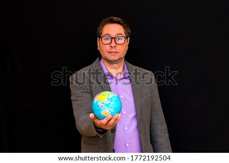 Front view image.Close up of businessman wears suit with eye glasses holding digital globe in palm global business communications concept.Black studio background.