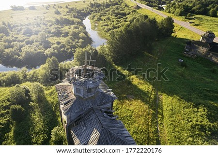 Top view of the old wooden church, green meadows in bright sunny colors. Photo of a landscape with a drone in summer
