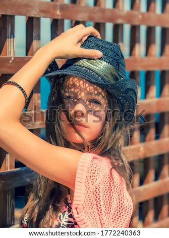 Summertime portrait of young girls in a swimsuit standing by the wooden fence