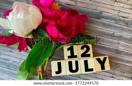 July 12. July 12 on wooden cubes on a wooden background.Peonies.Photos for the holiday .