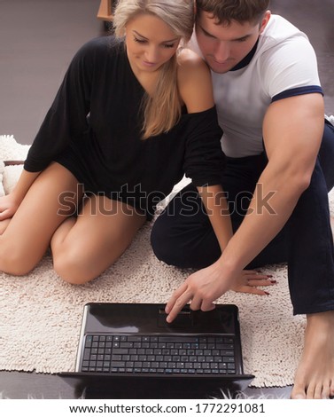 Planning summer vacation. Cute caucasian couple searching hotel and resort online, using laptop on floor at home. Happy couple doing online shopping together at home
