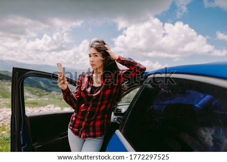 attractive woman travel by car and using smartphone in mountains. Beautiful female tourist on road trip by car to mountains browsing phone. Vacations summer time on lockdown.