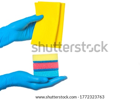 a hand in a blue glove holds multi-colored sponges and a yellow rag for cleaning rooms. on a white background.
