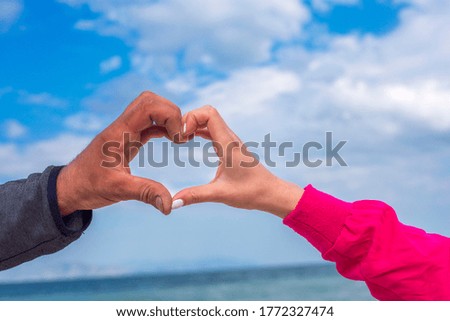 Two hand touch together in a heart shape on nature background.