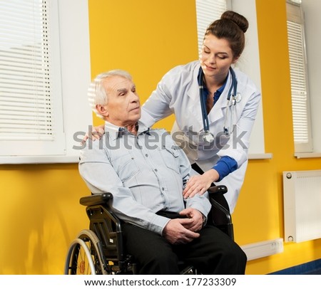 Cheerful young nurse woman with senior man in wheelchair 