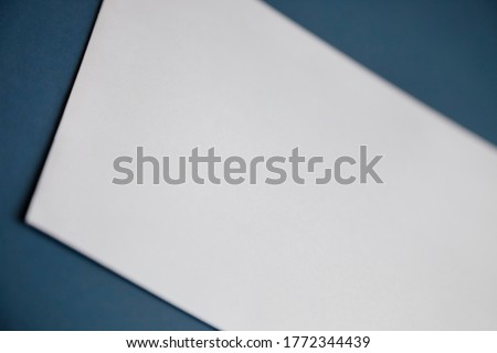 Cropped image of a blank white paper on dark blue surface