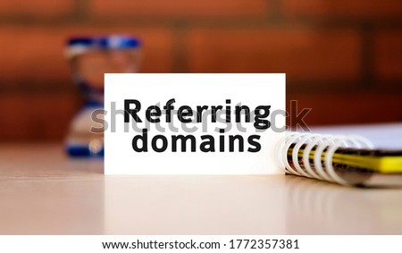 Referring domains - seo concept text n white sheet with notepad and hourglass