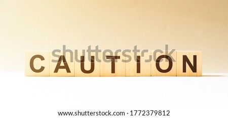 Man made word CAUTION with wood blocks