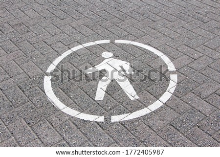 Pedestrian white sign in the circle painted on the brick pathway / walkway.