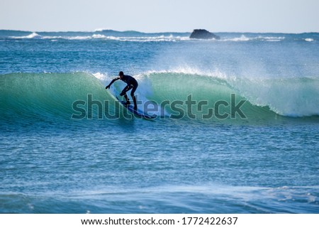 A surfer in a blue and green Ocean. Wave riding on surfing board in Asia.  Japan is famous for its great waves near to Tokyo City
