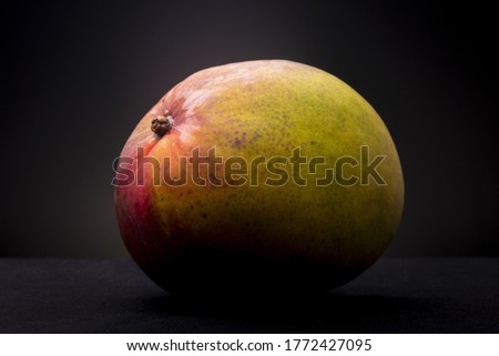 Colourful tropical red yellow orange ripe Mango fruit. Studio low key food still life against a dark background