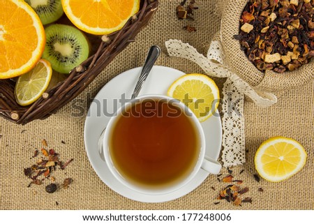 Hot cup of tea, herbal leaves and ripe fruits