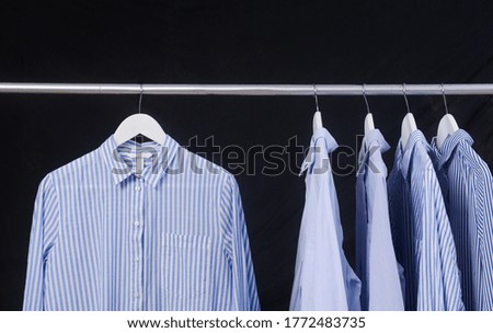 Striped with blue shirt with long sleeves isolated on hanger –black background
