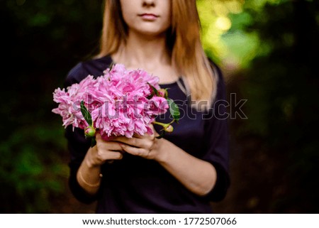 girl with flowers. A lady holds pink flowers in her hands. Peonies in the summer. Flowers of June.