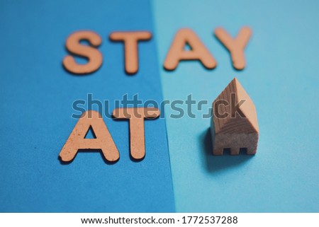 Stay at home message in 3d wooden alphabet letters and blocks placed on a pair of solid color background. Pandemic situation advice. Selective focus.