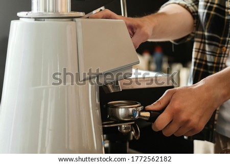 Closeup of barista grinding coffee. Professional barista working makeing coffee with coffee machine. Hot pouring drink concept. Toned picture