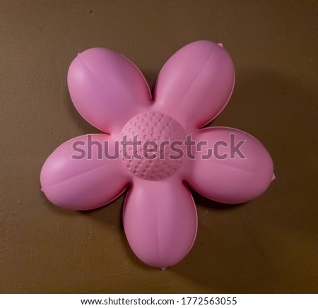 A pink of plastic flower isolated on a brown background.