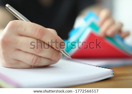 Man holds pen in his hand and writes in notebook. Startup development and drawing up business plan concept